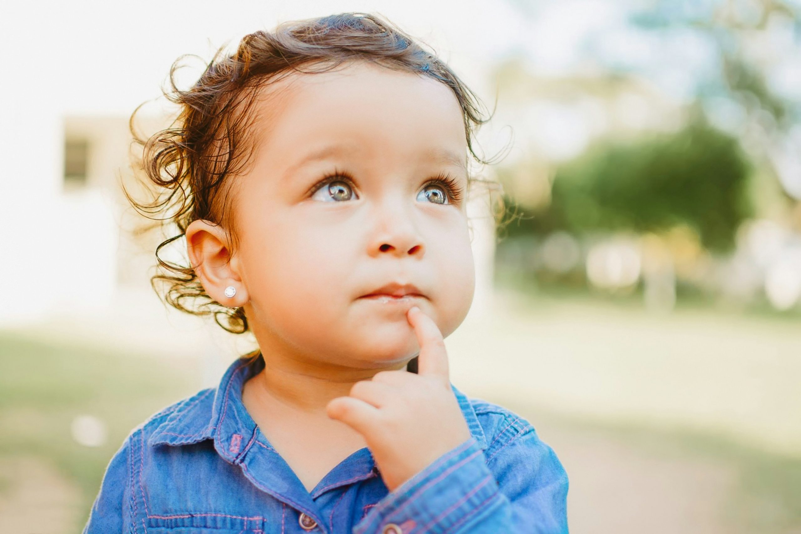 curious toddler with his index finger below his lip
